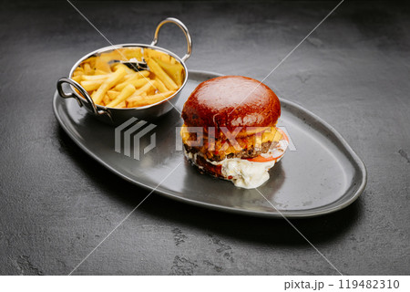 Juicy cheeseburger with crispy fries on black plate, meal for fast food lovers and comfort seekers 119482310
