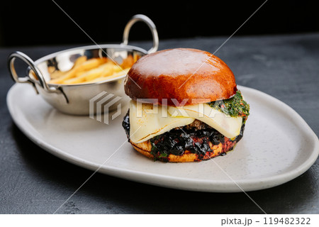 Gourmet burger with cheese, chimichurri, and fries, served on a stylish plate for an indulgent treat Gourmet burger with cheese, chimichurri, and fries, served on a stylish plate for an indulgent treat 119482322