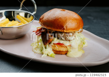 Juicy gourmet burger with melted cheese, bacon, and fries.Perfect for a delicious treat 119482323