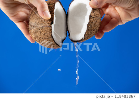 Hands open coconut, coconut water pour out, blue background Hands open coconut, coconut water pour out, blue background 119483867