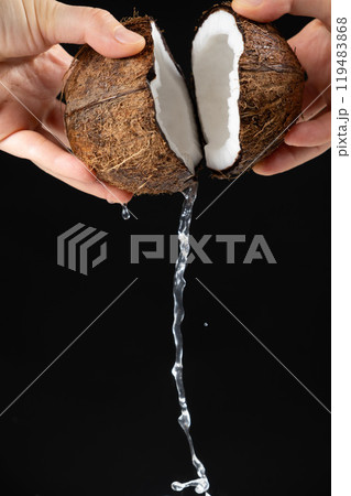 Hands open coconut, coconut water pour out, black background Hands open coconut, coconut water pour out, black background 119483868