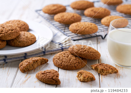 Low-calories oatmeal cookies and glass milk on a white table. 119484233