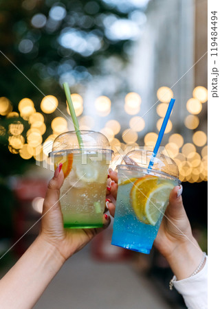Refreshing lemonades in vibrant colors, raised in a cheerful toast against glowing bokeh background Refreshing lemonades in vibrant colors, raised in a cheerful toast against glowing bokeh background 119484494
