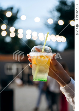 Refreshing lemonades in vibrant colors, raised in a cheerful toast against glowing bokeh background 119484495