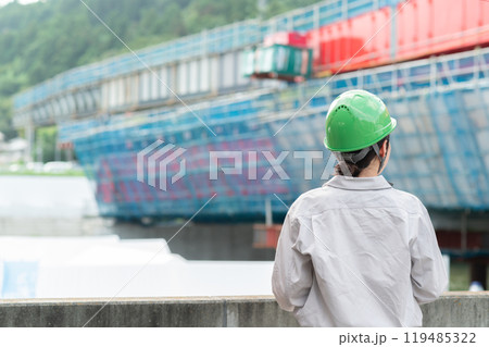建設中の橋を見つめるヘルメットを被った作業服姿の女性 建設中の橋を見つめるヘルメットを被った作業服姿の女性 119485322