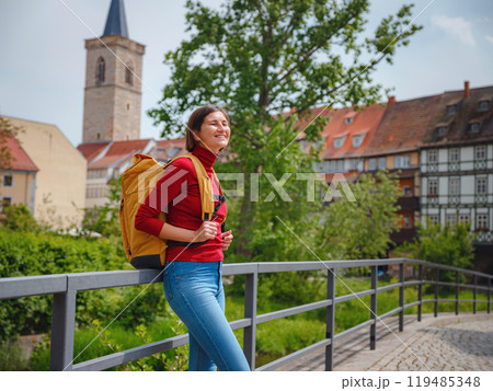 Tourist woman explores beautiful city of Erfurt, wandering through its historic streets, admiring charming architecture, and discovering cultural landmarks, fully immersed in citys rich heritage. 119485348