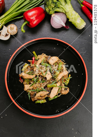 Stir-fried chicken with vegetables and glass noodles, garnished with sesame seeds for a healthy meal 119485378