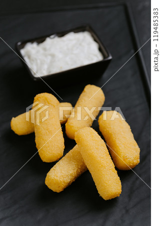 Golden crispy cheese sticks with a creamy dip, served on a sleek black plate. Perfect appetizer Golden crispy cheese sticks with a creamy dip, served on a sleek black plate. Perfect appetizer 119485383