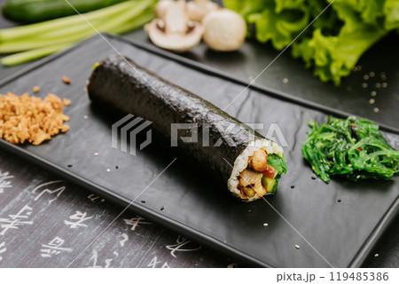 Gimbap roll with fresh vegetables, mushrooms and chicken, served with seaweed salad and fried onions Gimbap roll with fresh vegetables, mushrooms and chicken, served with seaweed salad and fried onions 119485386