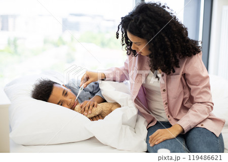 Mother caring for sick son in bedroom with thermometer 119486621