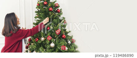 Banner Woman hands decorate Christmas tree red ball bauble. Panorama hands holding red ball bauble decorate. Wide shot Asian woman decor christmas tree in xmas season celebration with Copy Space Banner Woman hands decorate Christmas tree red ball bauble. Panorama hands holding red ball bauble decorate. Wide shot Asian woman decor christmas tree in xmas season celebration with Copy Space 119486890