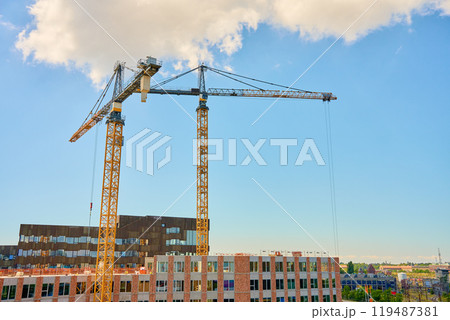 Two large tower cranes at construction site against clear blue sky. Modern building under development. Scandinavian architecture under construction 119487381