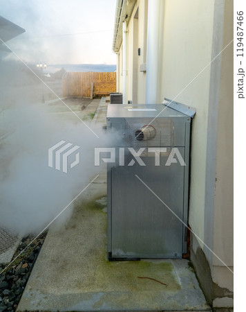 Steaming central heating boiler outside house in Ireland 119487466