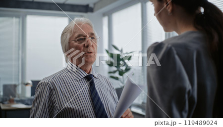 Senior boss of the company with papers talks to female financial specialist 119489024