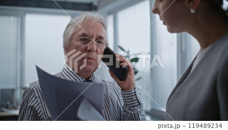 Senior boss of company talks to business client on mobile phone 119489234