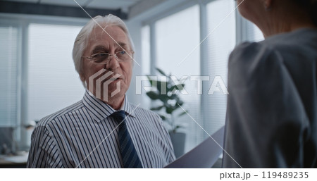 Senior boss of the company with papers talks to female financial specialist 119489235
