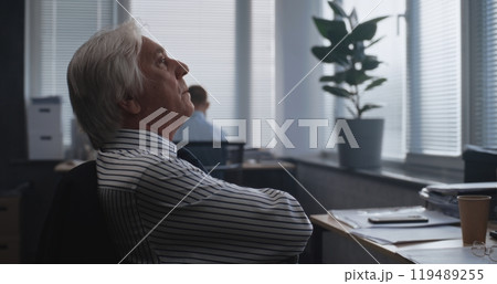 Tired senior financial specialist analyzes documents, monitors stock market on computer Tired senior financial specialist analyzes documents, monitors stock market on computer 119489255