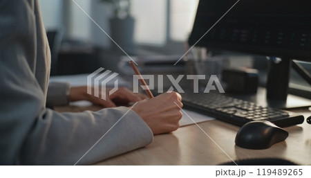 In modern office: Close up of female financial specialist taking notes In modern office: Close up of female financial specialist taking notes 119489265