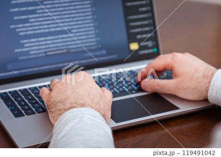 Close-up of male hands writing with pen on paper and using laptop. Modern remote work and business. Typing fingers on keyboard 119491042