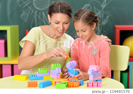 A mother and her daughter are assembling a construction set at home. 119491570