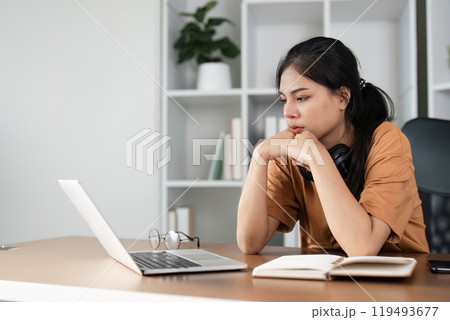 Young Woman Feeling Stressed While Studying Online at Home with Laptop and Books 119493677