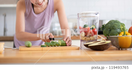 Young Healthy Woman Preparing Fresh Juice in Modern Kitchen with Fresh Vegetables and Fruits 119493765