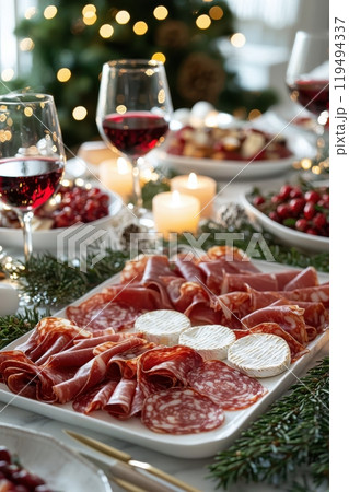 Festive Christmas table with charcuterie board, wine, and candlelight, creating a cozy holiday atmosphere 119494337
