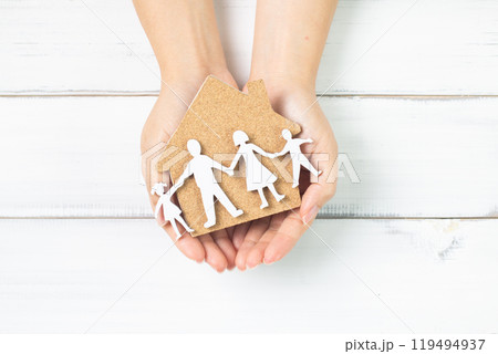 Protecting Family and Home: Hands Holding House Cutout and Paper Family Silhouettes 119494937