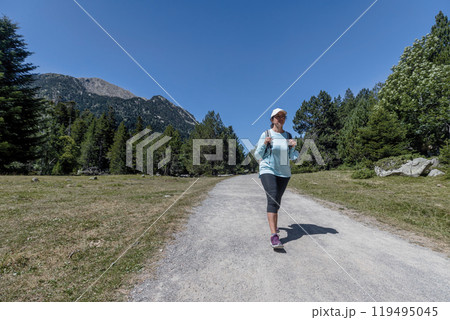 Young pretty tourist woman with backpack walking in a forest road 119495045