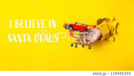 Hand holding a toy car in front of a yellow background 119495359