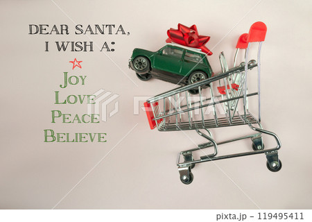 Green toy car is on top of a shopping cart with a red bow Green toy car is on top of a shopping cart with a red bow 119495411