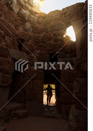Female traveler entering the mysterious Nuragic palace of Palmavera 119495633