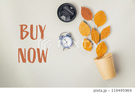 A clock and a cup of leaves are on a table with the words Buy Now 119495969