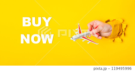 Hand holding a toy airplane with the words Buy Now written underneath Hand holding a toy airplane with the words Buy Now written underneath 119495996