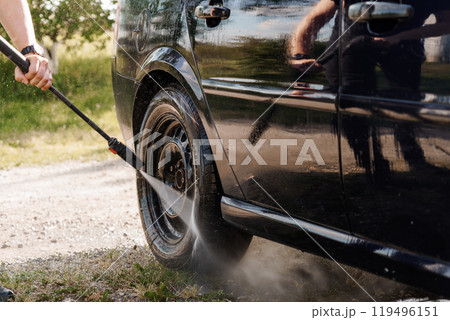 Dynamic Car Wash Scene Featuring a Gloved Hand Using a Pressure Washer on a Black Vehicle Wheel Dynamic Car Wash Scene Featuring a Gloved Hand Using a Pressure Washer on a Black Vehicle Wheel 119496151