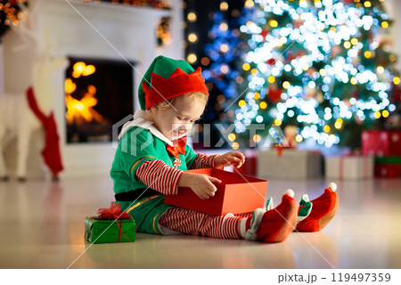 Kids at Christmas tree. Children open presents Kids at Christmas tree. Children open presents 119497359