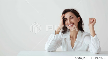A woman leans against a wall, smiling with her hand on her shoulder 119497929
