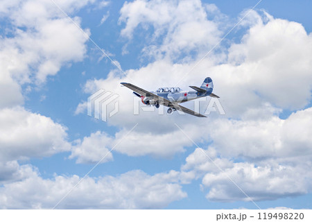 View of an aerobatic plane (aerodyne), in flight under a blue sky with white clouds. flight exhibitions View of an aerobatic plane (aerodyne), in flight under a blue sky with white clouds. flight exhibitions 119498220