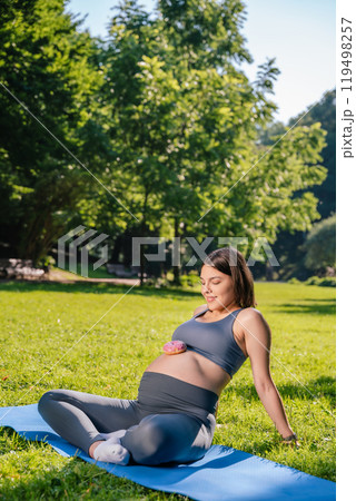 Girl with sugary cake on pregnant belly after physical activity outdoor 119498257