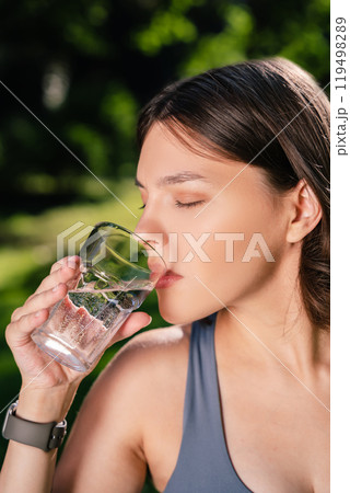 Future mother drinking water in park during pregnancy fitness workout 119498289