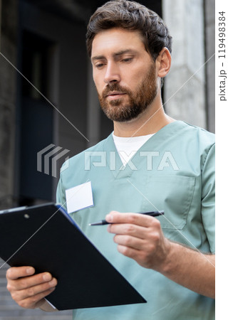 Male doctor writing prescription on clipboard outdoor of medical center 119498384