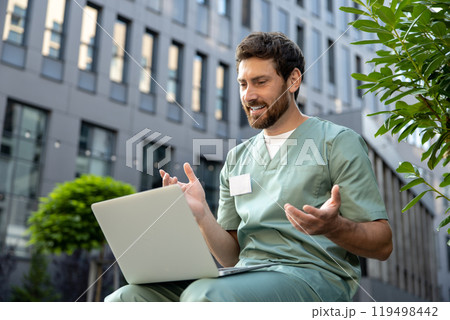 Doctor providing online medical consultation via video call on laptop near the hospital 119498442