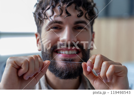Man with dental floss cleaning teeth and braces 119498543
