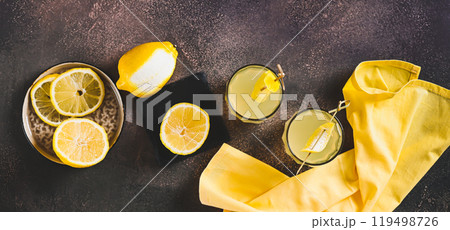Two glasses of Italian limoncello and lemons on the table top view web banner 119498726