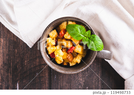 Close up of bread pudding with egg, pepper and basil in a cup on the table top view 119498733