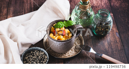 Bread pudding with egg, pepper and basil in a cup on the table web banner 119498736