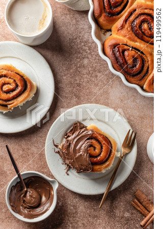 Chocolate swirl buns with hazelnut chocolate filling. Chocolate cinnamon buns and coffee served for breakfast on brown background top view 119499562