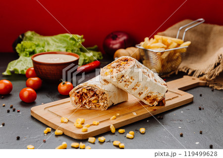 Juicy BBQ chicken wrap with corn filling, cut and styled on board. Ideal for fast-food lovers 119499628