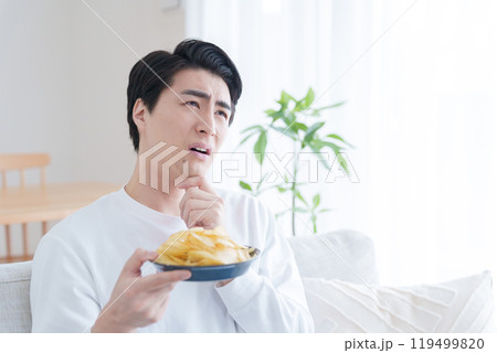 ポテトチップスを食べるか悩む男性(ポテチ・ダイエット・太る・不健康) ポテトチップスを食べるか悩む男性(ポテチ・ダイエット・太る・不健康) 119499820