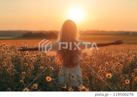 Woman enjoying sunset in sunflower field with open arms 119500276